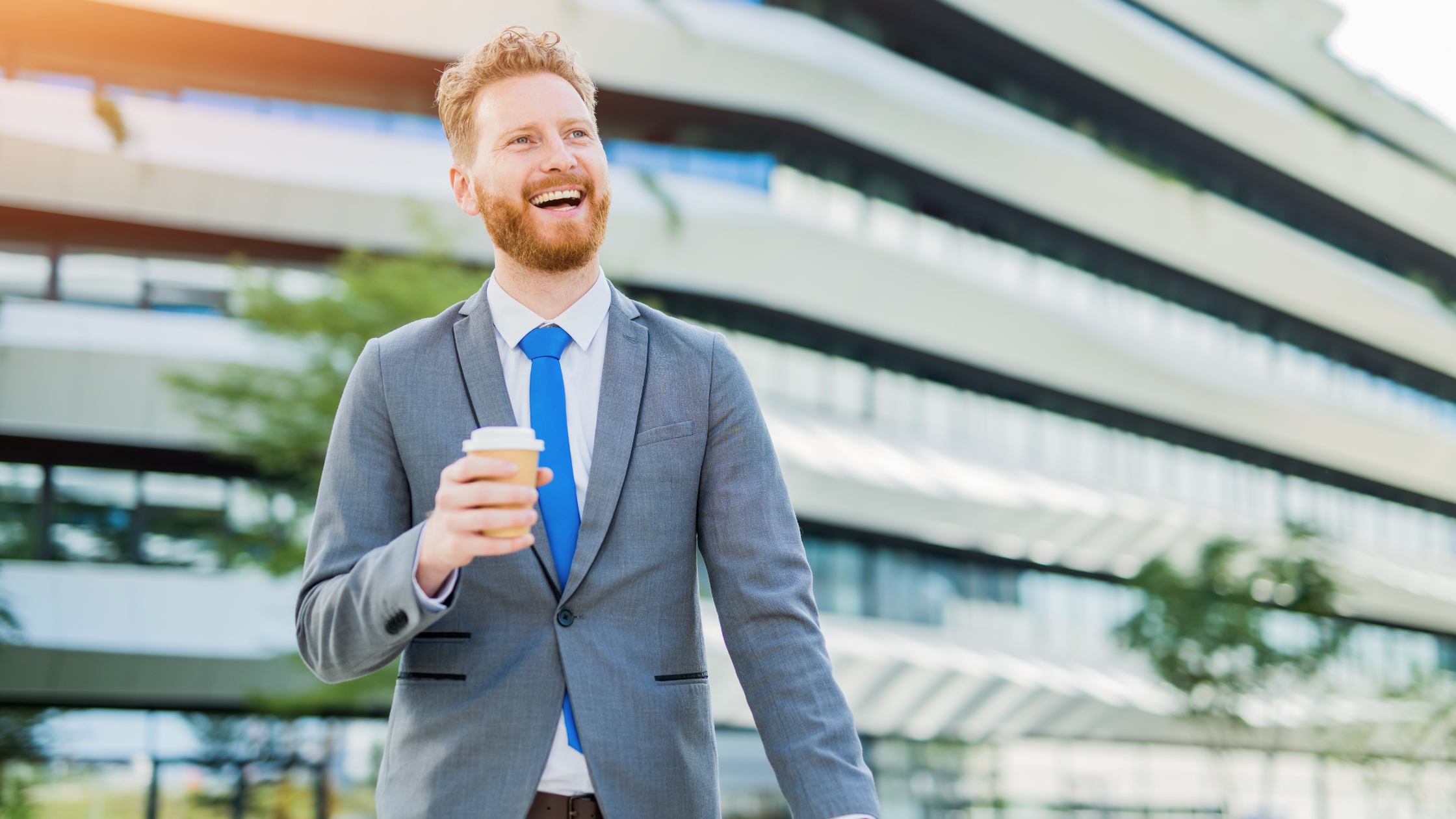 Smiling man in suit holding coffee cup outdoors