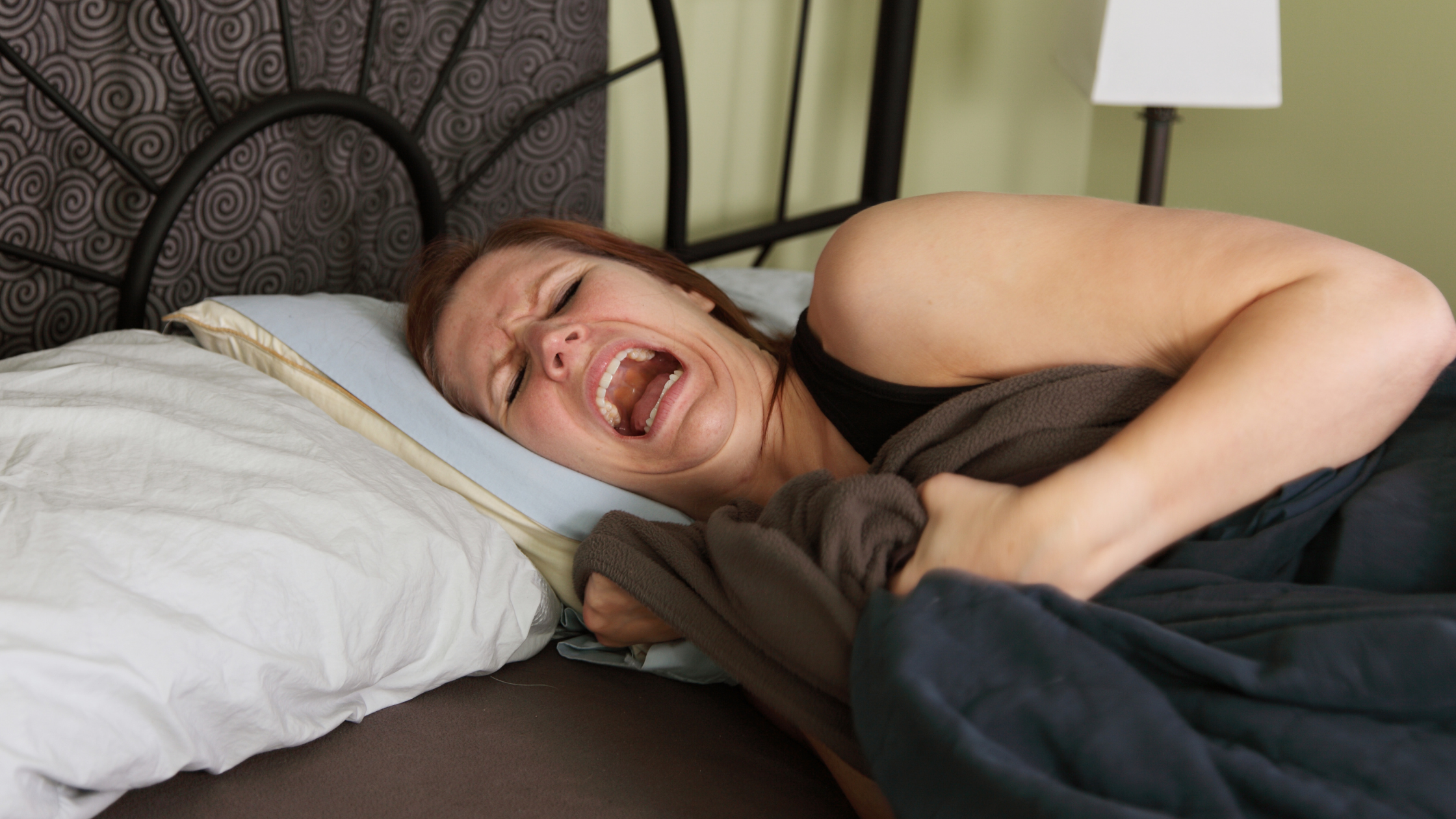 Person in bed appearing distressed, clutching blanket