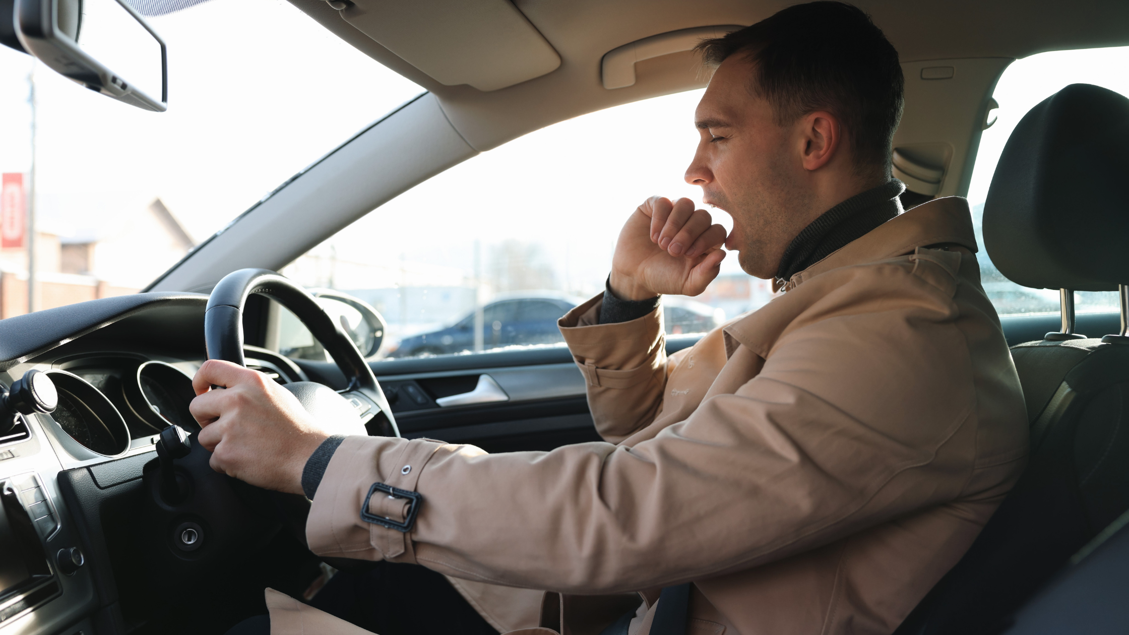 Tired man yawning while driving a car