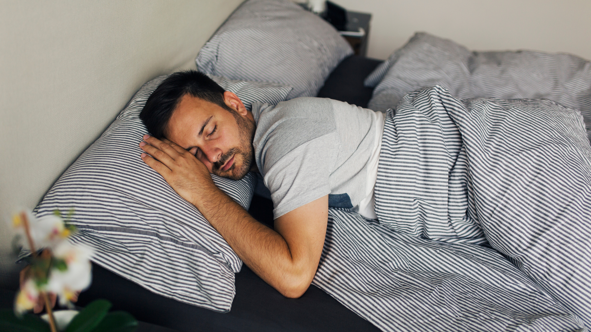 Person lying in bed in a dark, calm bedroom practicing deep breathing techniques to fall asleep fast, with a clock showing late night hours.
