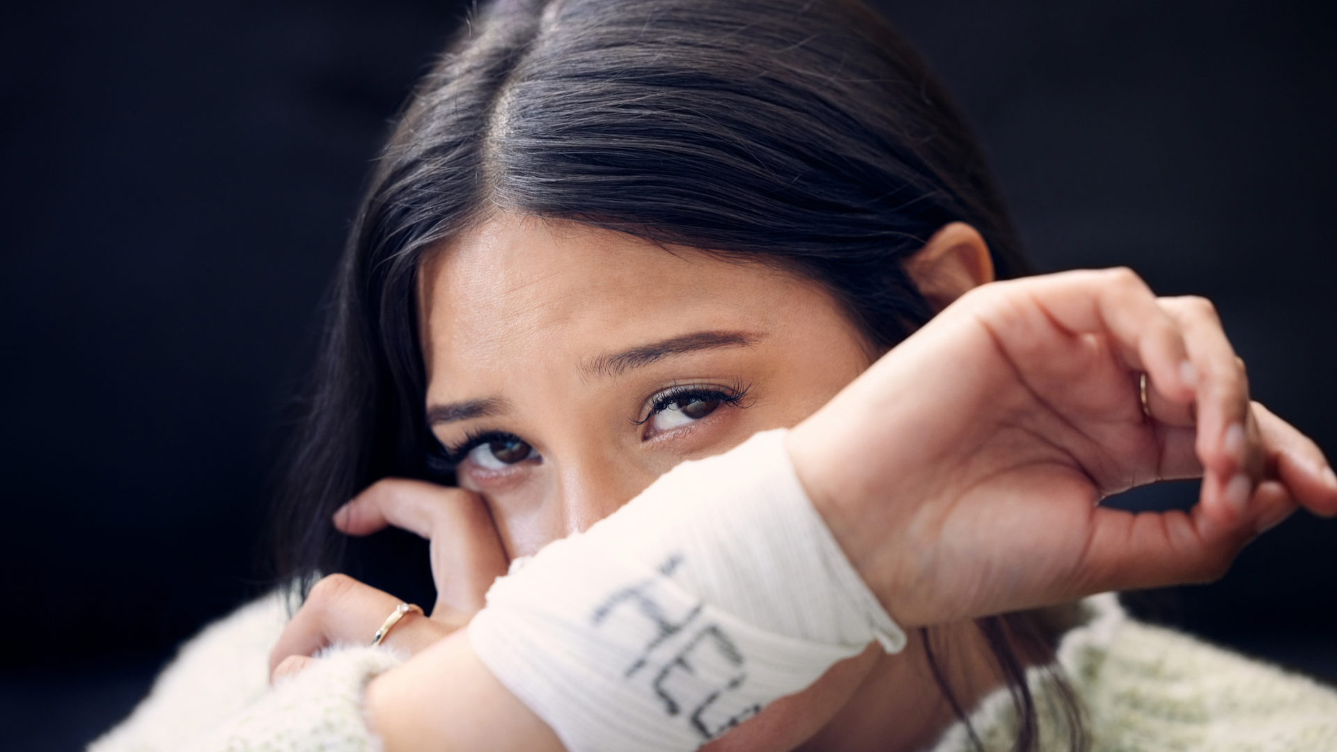 A person sitting alone with their head in their hands, surrounded by supportive messages and a phone, symbolizing coping with suicidal thoughts.