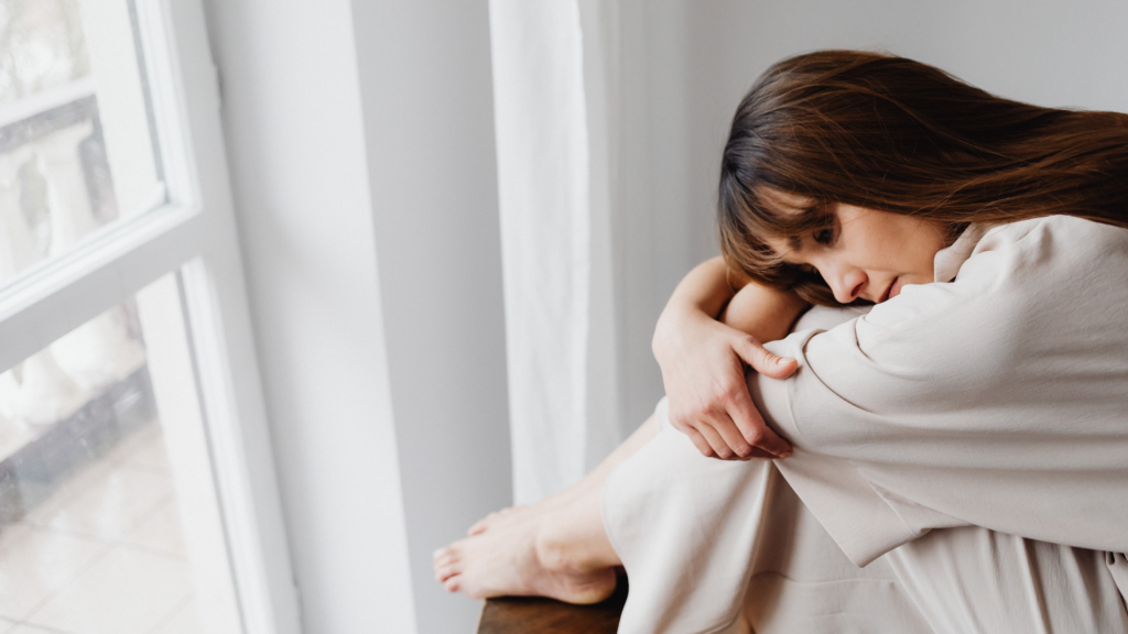 A person sits quietly with eyes closed, practicing mindfulness meditation to cope with emotional pain and promote inner healing and self-care.