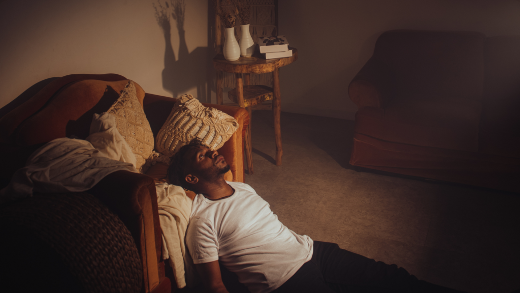 A person sits alone on a park bench, looking downcast and withdrawn, symbolizing the loss of enjoyment of life and diminished daily happiness.