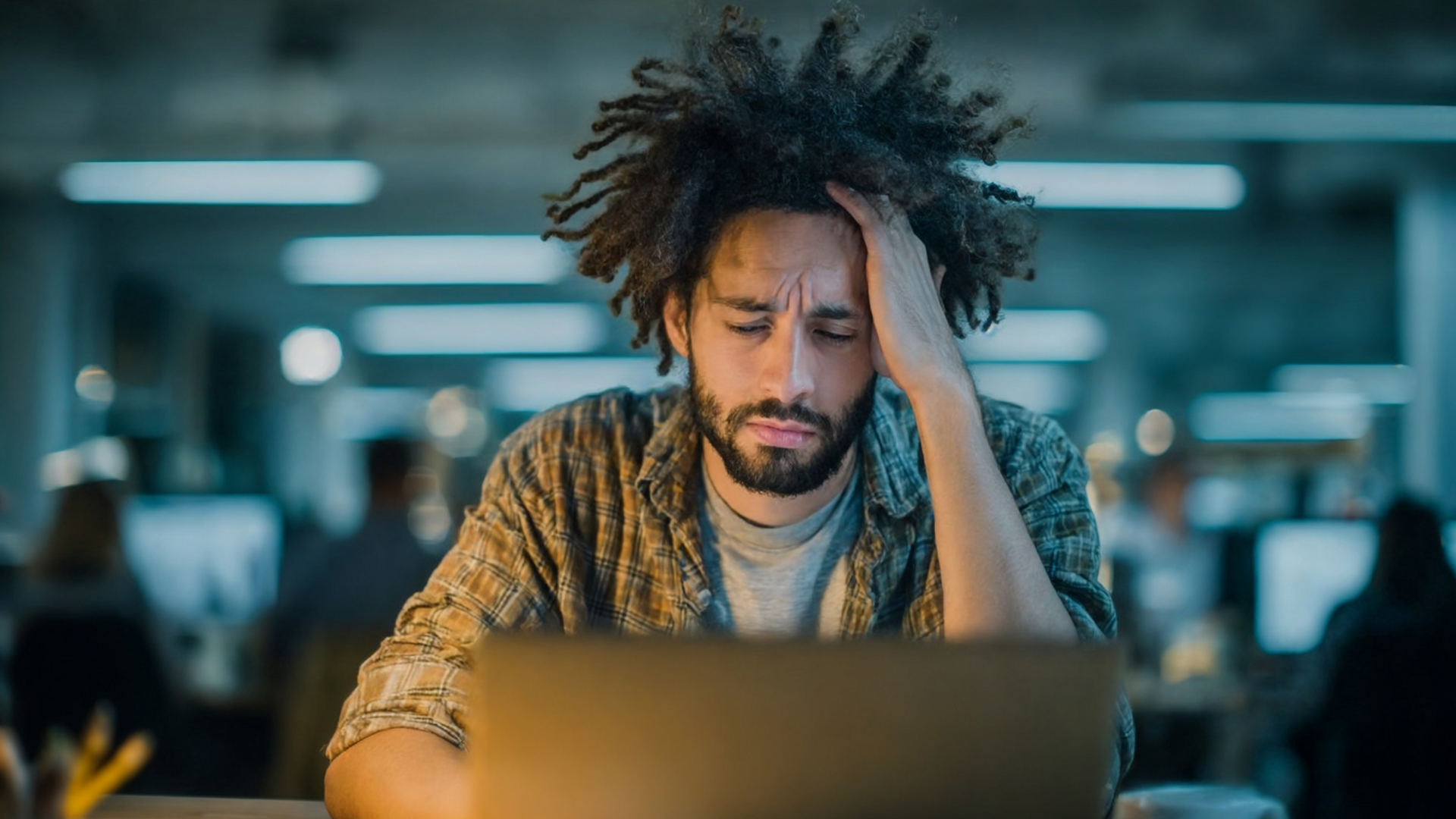 A stressed employee sits at a desk with head in hands, paperwork scattered, symbolizing the need for stress leave from work due to burnout.