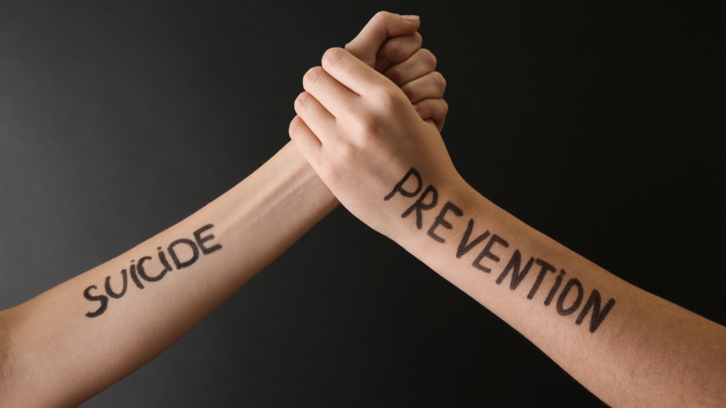 A person sits with a supportive friend, holding hands and talking, symbolizing emotional support and connection for suicide prevention.