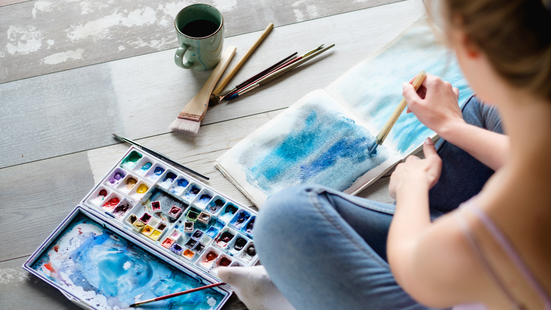 A group of people engaging in art therapy activities, painting and drawing together in a bright, supportive studio environment to promote emotional healing.