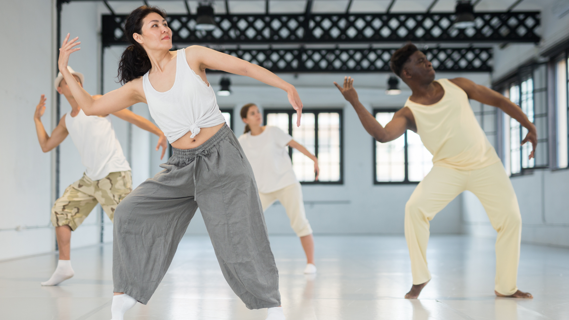 A therapist guides a group session in dance movement therapy, where participants express emotions and improve well-being through guided body movements.