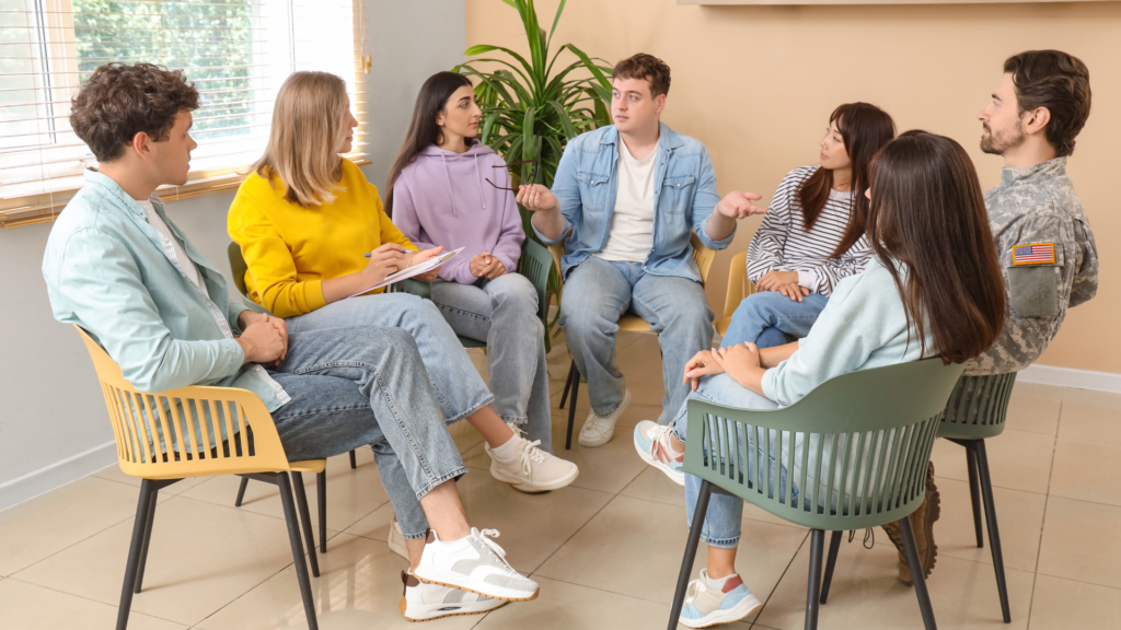 A group of people sitting in a circle, participating in a guided group therapy activity, sharing experiences and engaging in supportive discussion.