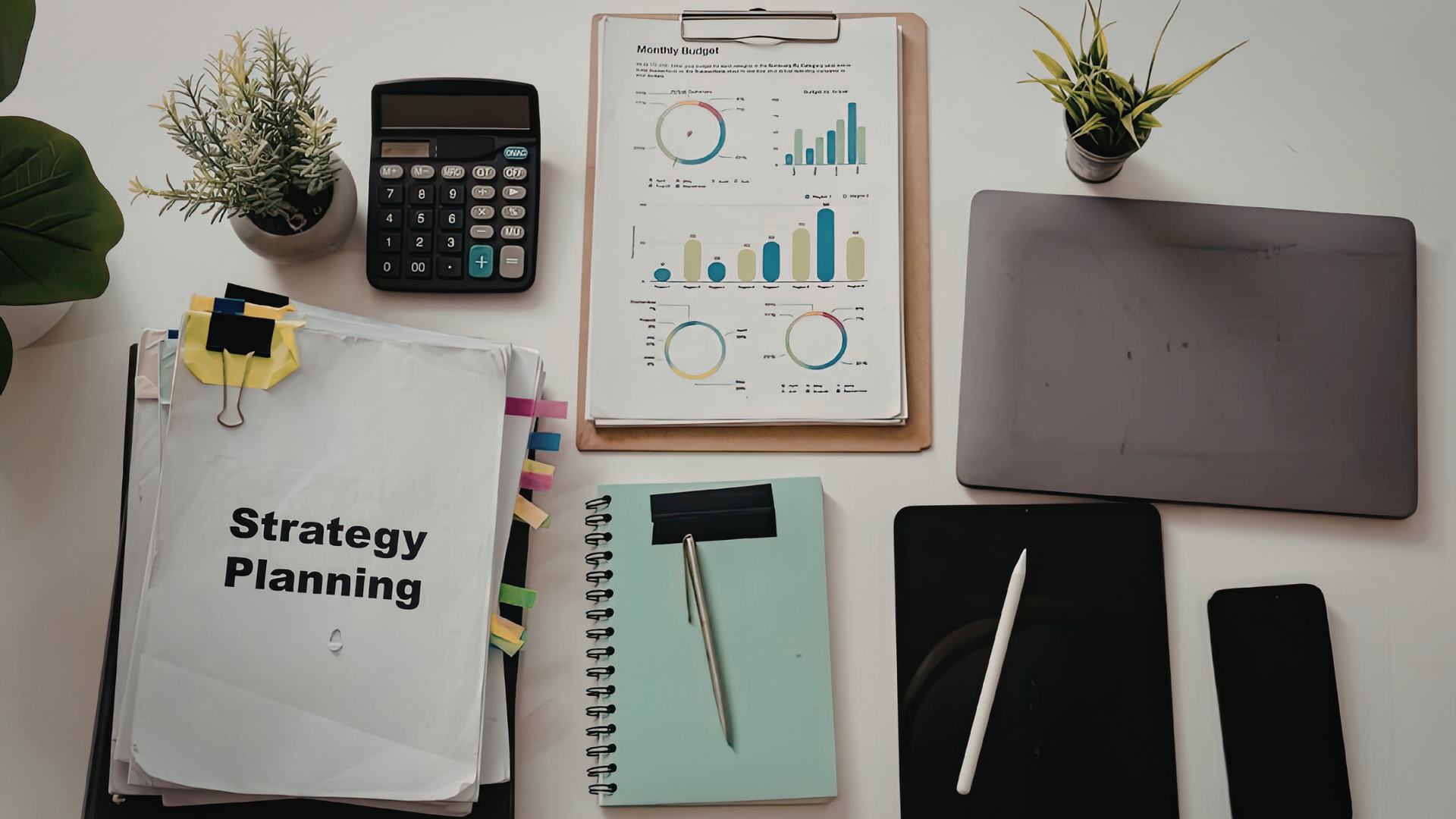 A tidy desk with labeled storage boxes, organized stationery, a laptop, and a planner, illustrating effective workspace organization techniques.