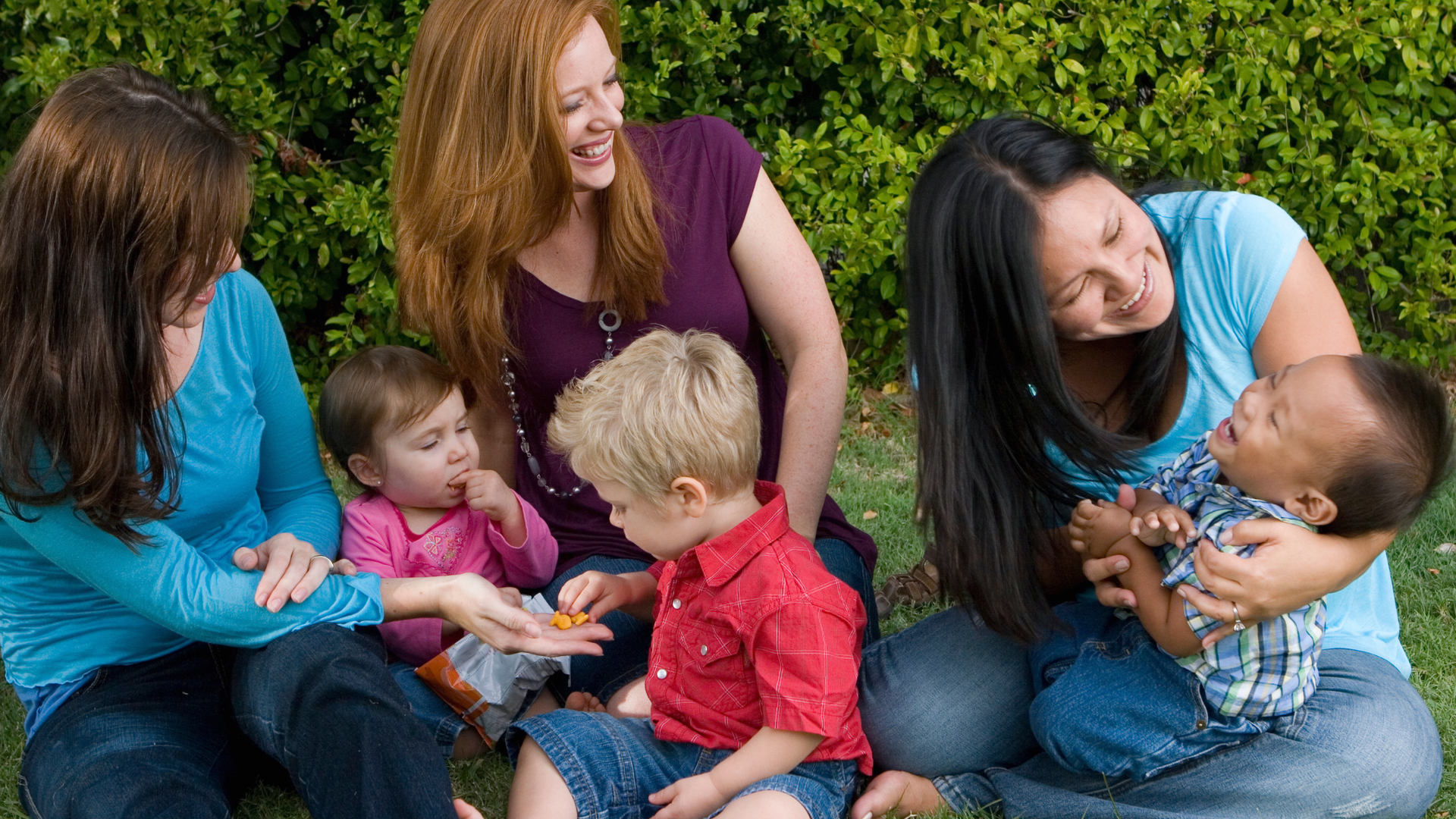 A diverse group of moms sitting in a circle, sharing experiences and offering support at a local mom support group meeting.