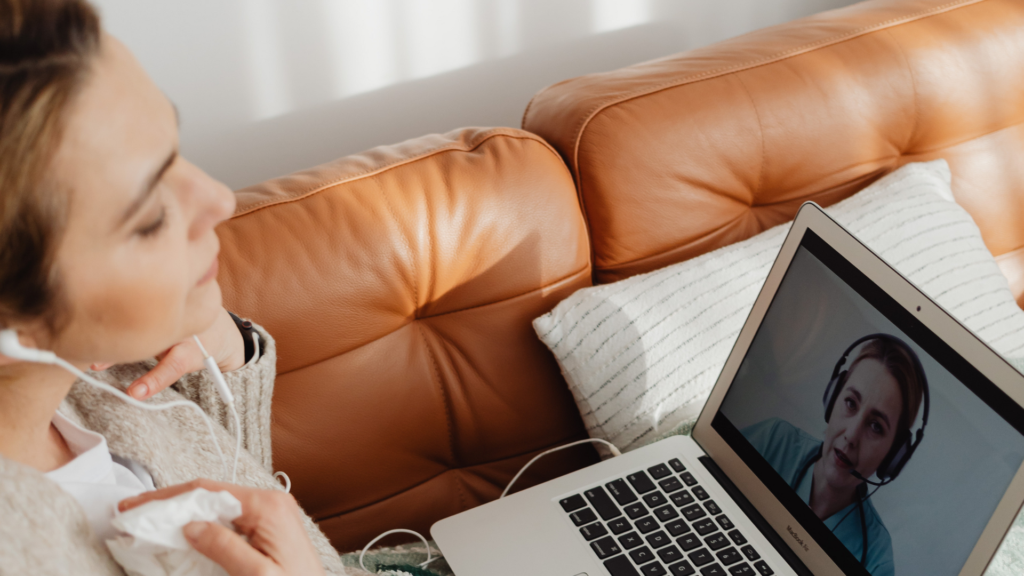 A person attends an online therapy session on a laptop to manage panic attacks, with a therapist visible on the screen offering support and guidance.