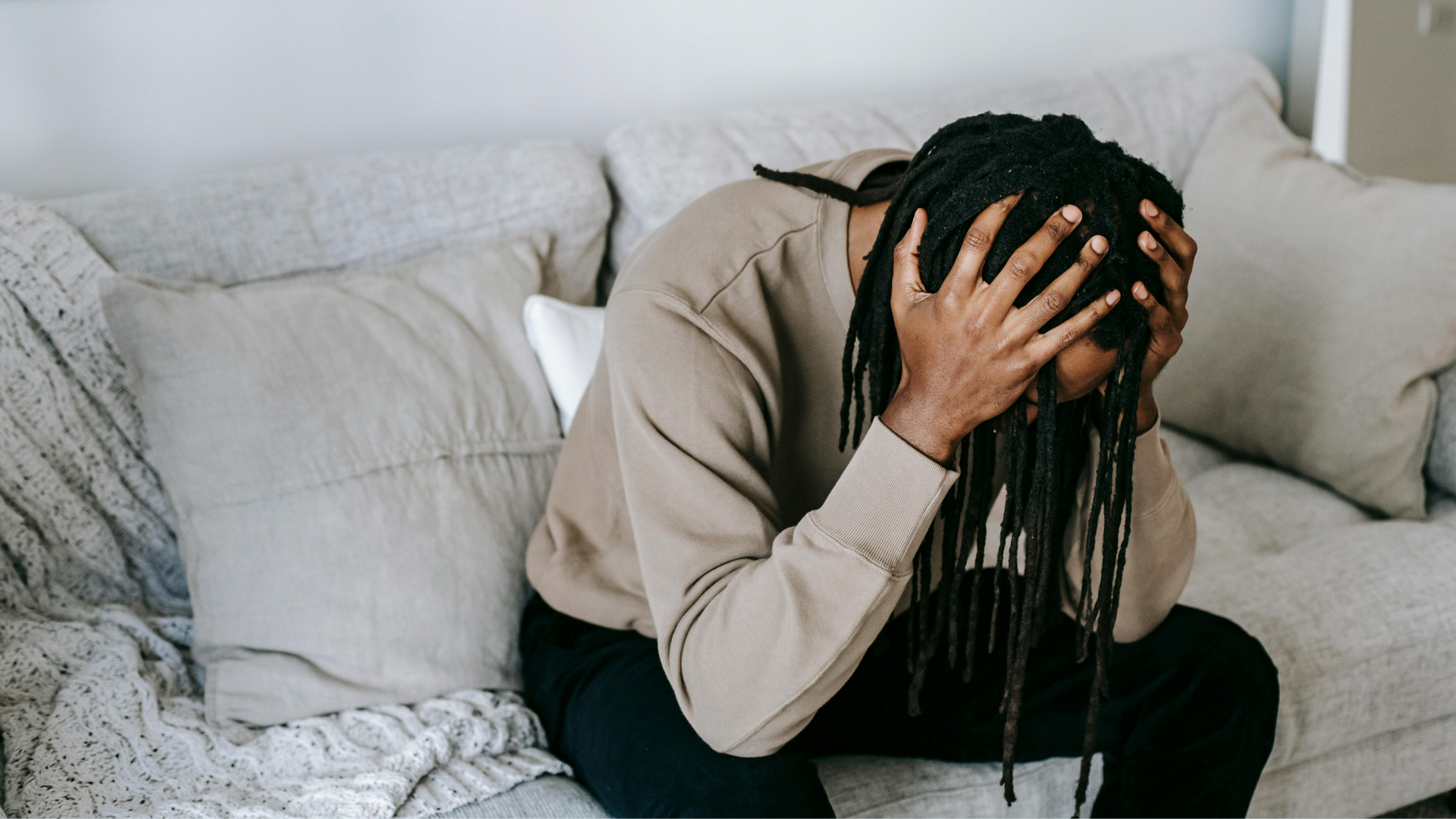 A person sits alert in a dimly lit room, eyes wide and tense, scanning their surroundings, illustrating the constant state of hypervigilance.